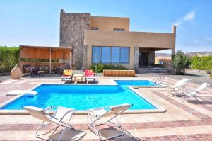 a swimming pool with chairs and a house at Luxury Sea-View Villa with Private Pool with Diving center & Beach access in Marsa Alam City