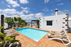 een zwembad met ligstoelen en een huis bij Spacious Private Villa up to 16 - Authentic Yaiza - Volcano, Timanfaya park, Bodega & South Beaches - Heated Pool - Game Room - Charcoal grill in Yaiza