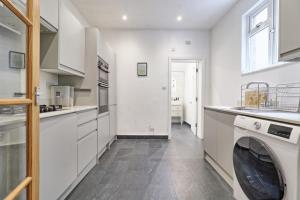 a kitchen with white cabinets and a dishwasher at Ivy on Sea Villa in Southend-on-Sea