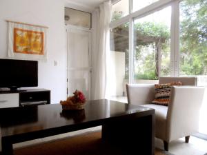 sala de estar con mesa, sillas y TV en Terrazas de Carilo 1A en Cariló