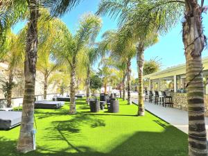 a park with palm trees and tables and chairs at Corfu Hotel in Ayia Napa
