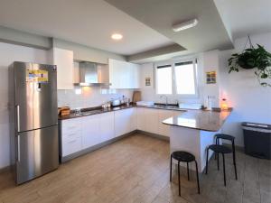 a kitchen with white cabinets and a stainless steel refrigerator at Albergue de Sonia in Finisterre