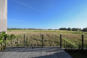 a wooden boardwalk with a field in the background at Cozy 2BR Villa at Kedungu in Tabanan