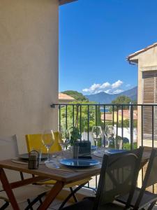 a wooden table with wine glasses on a balcony at Appartement HARMONIE in Saint-Florent