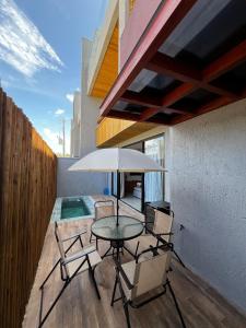 a patio with a table and chairs and an umbrella at Casa Villa Kamai 01 in São Miguel dos Milagres