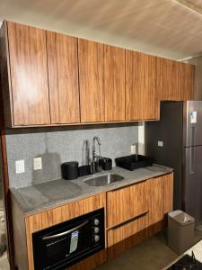 a kitchen with wooden cabinets and a sink and a refrigerator at Casa Villa Kamai 01 in São Miguel dos Milagres