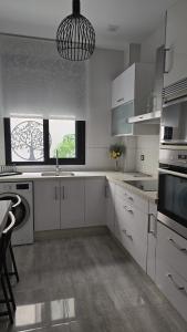 Málaga Centro, 2 habs, Piscina en azotea, 2 terrazas y parking privado في مالقة: مطبخ فيه دواليب بيضاء و قلادة خفيفة