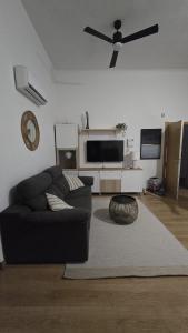 Málaga Centro, 2 habs, Piscina en azotea, 2 terrazas y parking privado في مالقة: غرفة معيشة مع أريكة سوداء ومروحة سقف