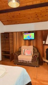 a living room with a couch and a flat screen tv at Chalés Raios de Sol in Monte Verde +22 photos