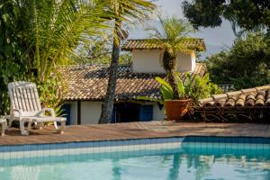 a villa with a pool and a chair next to a house at Ilhabela Homestay in Ilhabela