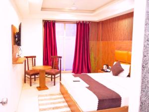 ニューデリーにあるHotel Air City Near Delhi Aiportのベッド、テーブル、椅子が備わるホテルルームです。