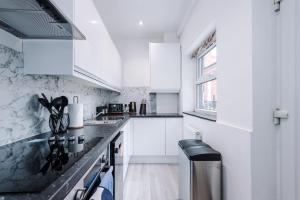 uma cozinha com armários brancos e bancadas pretas em Spacious 5 bedroom house near Leeds City Centre sleeps 12 suits contractors with free parking em Hunslet