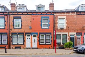 um edifício de tijolos vermelhos com portas e janelas brancas em Spacious 5 bedroom house near Leeds City Centre sleeps 12 suits contractors with free parking em Hunslet