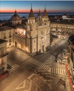 ein großes Gebäude mit einem Uhrturm in einer Stadt in der Unterkunft SAVOIA 173 - Apartment in Acireale