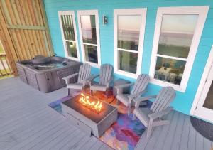 a deck with a fireplace and chairs and a hot tub at Beachfront - Hot Tub - Home Theater in Bolivar Peninsula