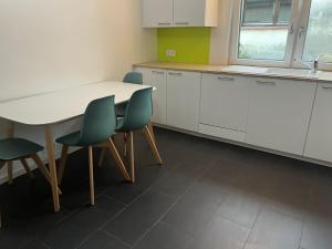 une cuisine avec des placards blancs, des chaises vertes et une table dans l'établissement Süße Marie Rüppurr Apartment 1, à Karlsruhe 6 autres photos
