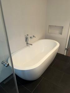 La salle de bains est pourvue d'une baignoire blanche et de carrelage noir. dans l'établissement Süße Marie Rüppurr Apartment 1, à Karlsruhe