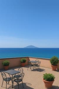 a patio with tables and chairs and the ocean at ApartHotel Del Corso in Castiglione della Pescaia