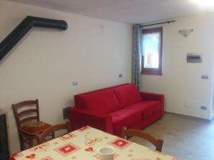 - un salon avec un canapé rouge et une table dans l'établissement Les Racines, à Rhêmes-Notre-Dame