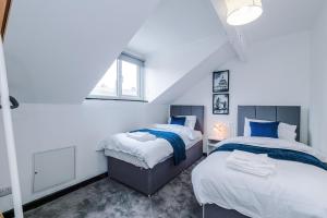 um quarto com duas camas e uma janela em Spacious 5 bedroom house near Leeds City Centre sleeps 12 suits contractors with free parking em Hunslet