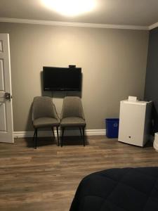 a living room with two chairs and a flat screen tv at Stanley House Motel in Clarenville