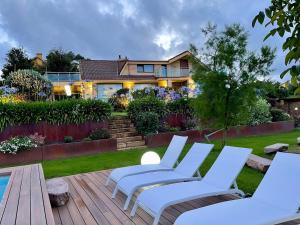 a group of chairs sitting on a deck next to a house at Stylish Host Cantabria- Lujosa villa en Bezana in Santa Cruz de Bezana
