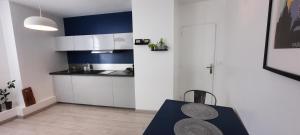 a kitchen with white cabinets and a blue wall at La Petardière in Meaux