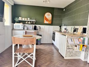 a kitchen with green walls and a table and chairs at Idéal couple - La Petite Oasis - 10min à pieds du centre ville & plage - 2km du Centre Juno Beach - 23min du Mémorial de Caen - wifi gratuit in Courseulles-sur-Mer +9 photos
