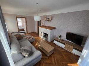 Una sala de estar con un sofá y un televisor de pantalla plana. en White House Apartment, en Jūrmala