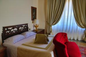 a bedroom with a bed and a red chair at Hotel La Collegiata in San Gimignano