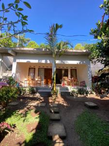 a house with chairs and a palm tree in front of it at Vanilla Cottage Tetebatu in Tetebatu +34 photos