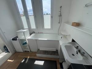 a white bathroom with a tub and a sink at Appartement à 50m de la Plage A in Arcachon