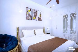a white bedroom with a bed and a blue chair at Hoài An Villa - Biệt thự 7 Pngủ - 100m đến bãi biển in Ha Long +39 photos