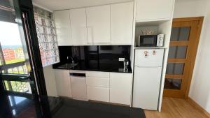 a white kitchen with a refrigerator and a microwave at A Orillas de Llas in Foz