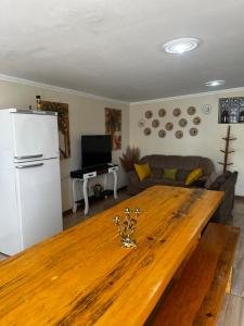 a living room with a wooden table and a white refrigerator at Recanto das Corujas in Campos do Jordão