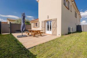 a wooden deck with a picnic table and an umbrella at Belle maison climatisée - MEET - Aeroscopia - TRAMWAY in Aussonne