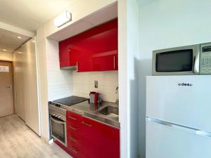 cocina con armarios rojos y nevera blanca en Apartsalou Masia, en Salou