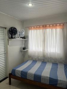 a bedroom with a bed and a window with a fan at Casa temporada Guarapari in Guarapari