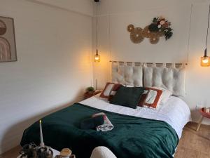 a bedroom with a large bed with a green blanket at L'écrin de la villa des roses in Pontmain