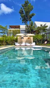 a swimming pool with a chair and an umbrella at Bacana Bungalow in Uluwatu