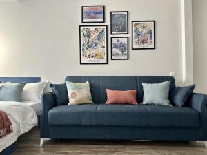 a blue couch in a bedroom with pictures on the wall at Студия ПРОВАНС в центре Алматы in Almaty