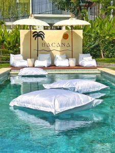 a swimming pool with white pillows and umbrellas at Bacana Bungalow in Uluwatu