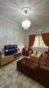a living room with couches and a television and a chandelier at Cozy Apartment In East Legon Room 4008 in Accra