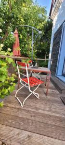 a red chair and a table on a deck at Fast wie zu Hause in Jettingen-Scheppach