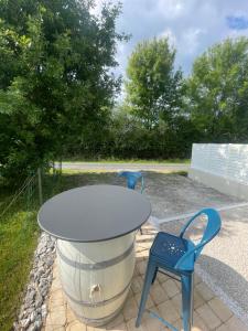 a table and two blue chairs on a patio at Maison avec grand espace en hauteur in Saint-Georges-des-Côteaux
