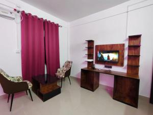 a room with a desk with a television and two chairs at Rema Guest House in Itānagar