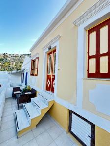 a balcony of a house with stairs and a red door at Seaside escape in Symi