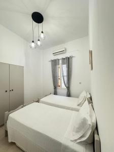 a white bedroom with two beds and a window at Seaside escape in Symi