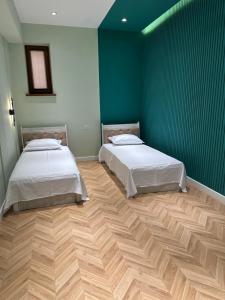 Cette chambre comprend 2 lits dans une chambre dotée de murs verts et de parquet. dans l'établissement Новая квартира с евро ремонтом, à Samarcande