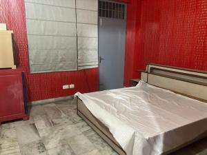 a bedroom with a bed and a red wall at Golden Triangle in Jāmb